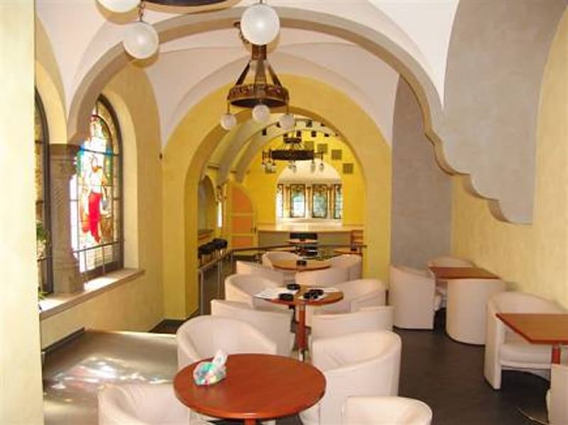 yellow walls, arched ceilings, white chairs, wooden tables, stained glass window