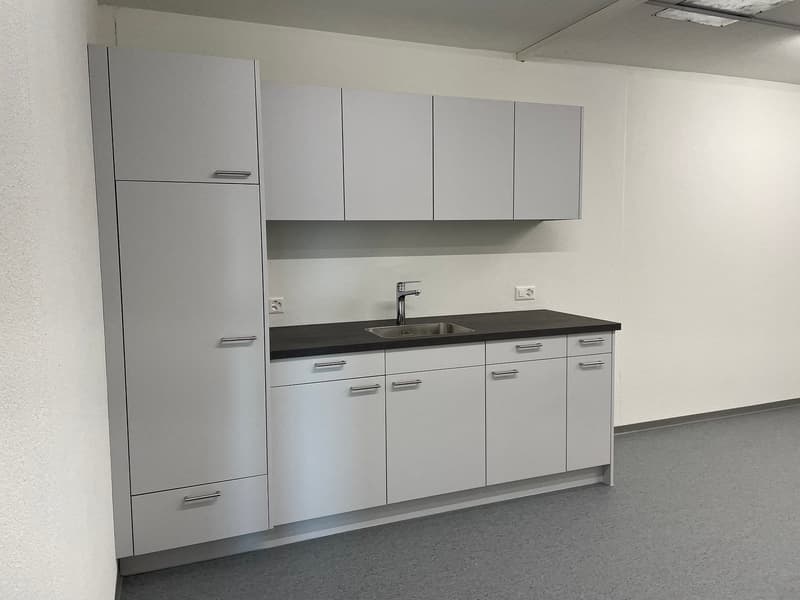 modern kitchen with white cabinets, black countertop, stainless steel sink, gray floors