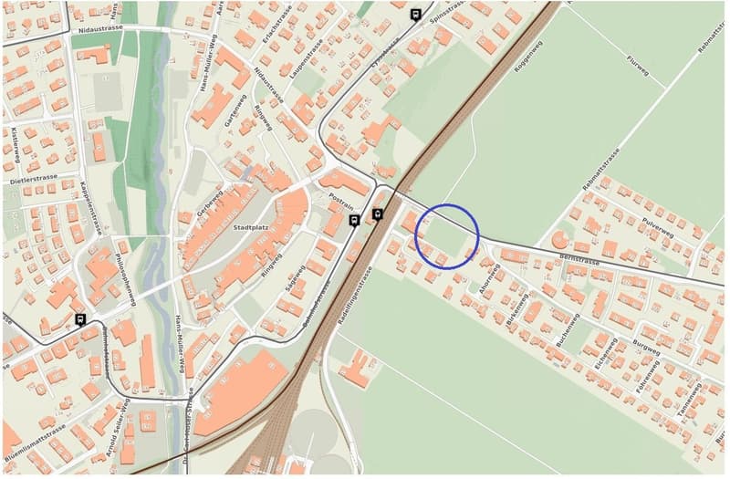 This is a detailed map of a town or city. The map shows various streets, buildings, and landmarks. The area circled in blue appears to be a parking lot or parking area.