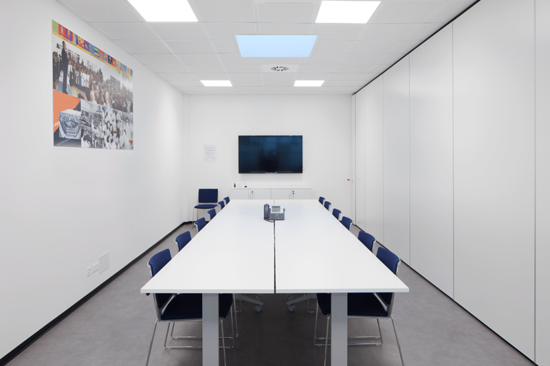conference room, long table, blue chairs, mounted TV, white walls