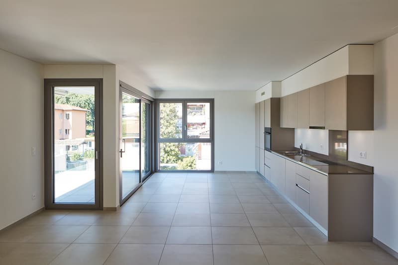 empty room, large windows, sliding glass doors, tiled floor, kitchen area