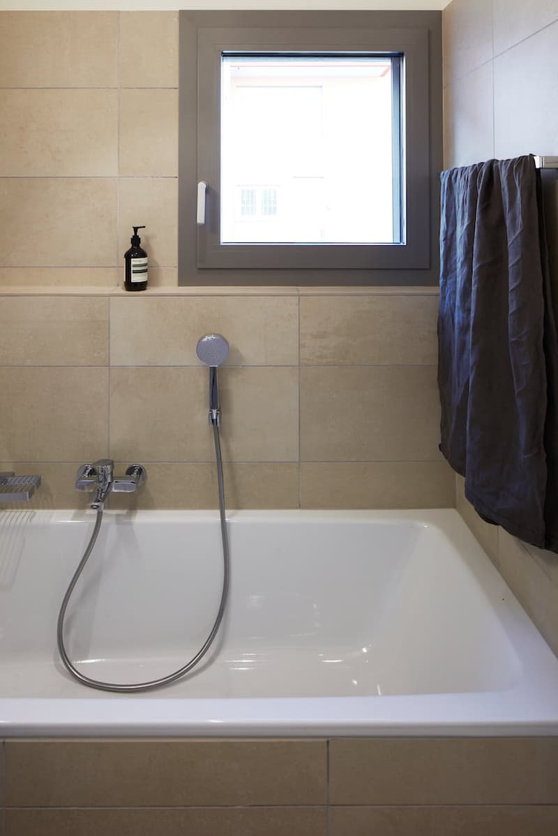 Bathtub, shower head, faucet, window, towel rack, soap dispenser