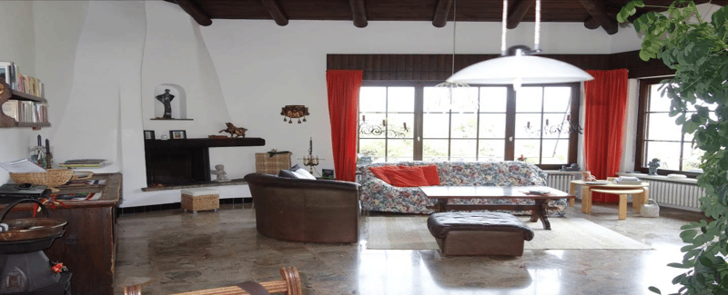 fireplace, sofa, coffee table, armchair, rug, bookshelves, desk, windows with red curtains