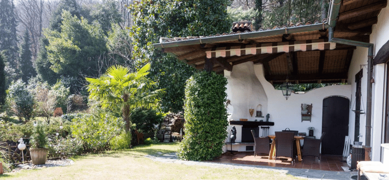 patio with tile floor, wooden awning, dining table and chairs, fireplace, garden