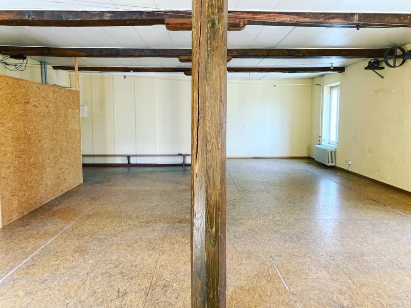 spacious room, wooden beams, wooden pillar, white walls, window with heater