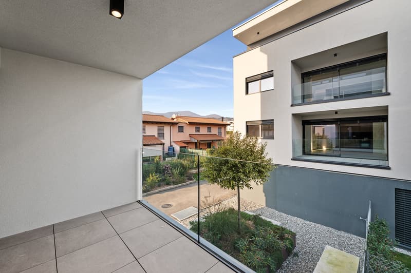 Spacious apartment with a balcony overlooking a well-maintained garden area. The apartment features large windows, providing ample natural light and a view of the surrounding buildings and landscape.