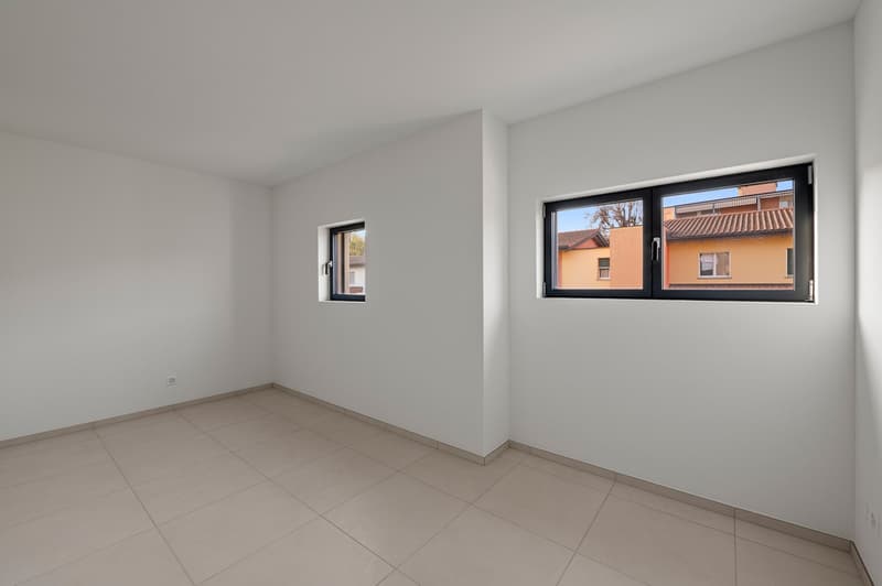 Empty room with white walls, large windows, and tile flooring