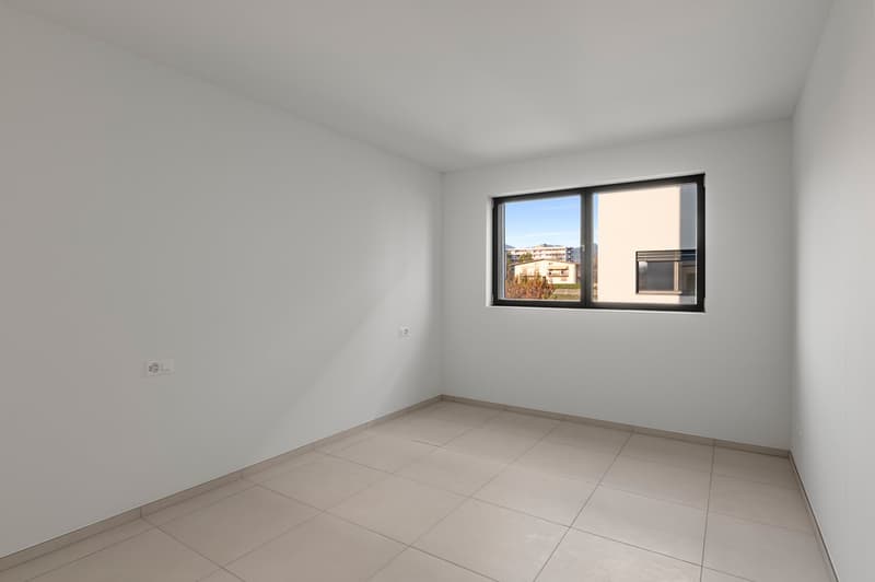Empty room with white walls, large window, and tile flooring.
