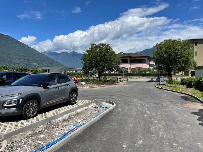 Empty road with parked cars, trees, mountains in the background, under construction