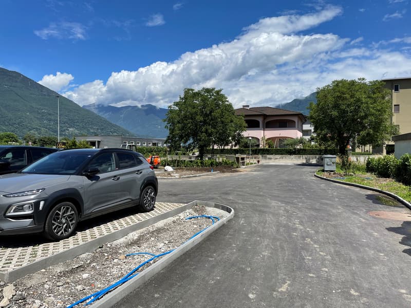 Empty road with parked cars, trees, mountains in the background, under construction