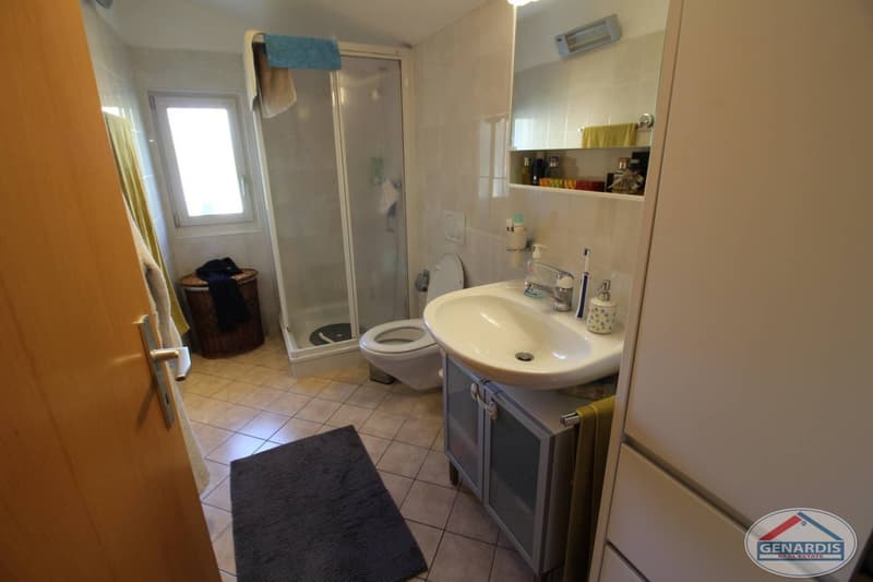white tile flooring, glass shower enclosure, white toilet, white sink, mirror, towel holder, toiletries shelf