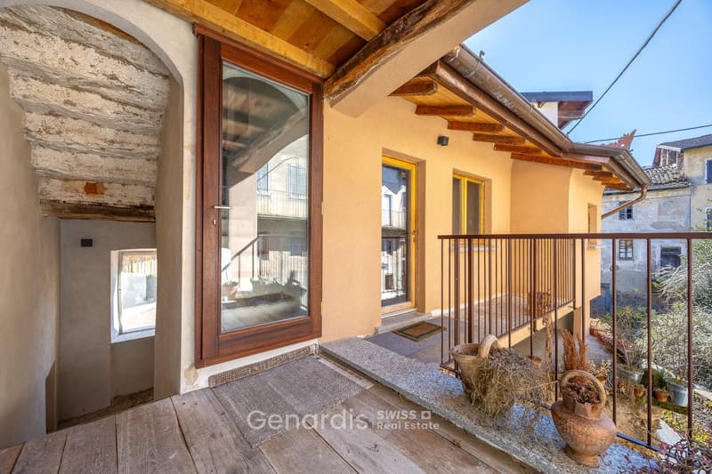 exterior of a house with wooden balcony, glass door, wooden floor, beige walls, small window