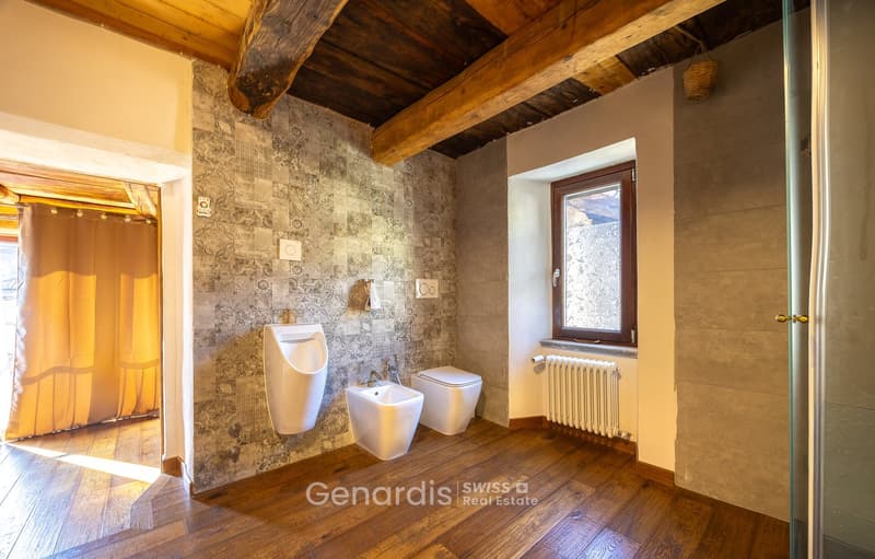 Bathroom with wooden floor, white walls, white fixtures, radiator, window, urinal, sink, toilet