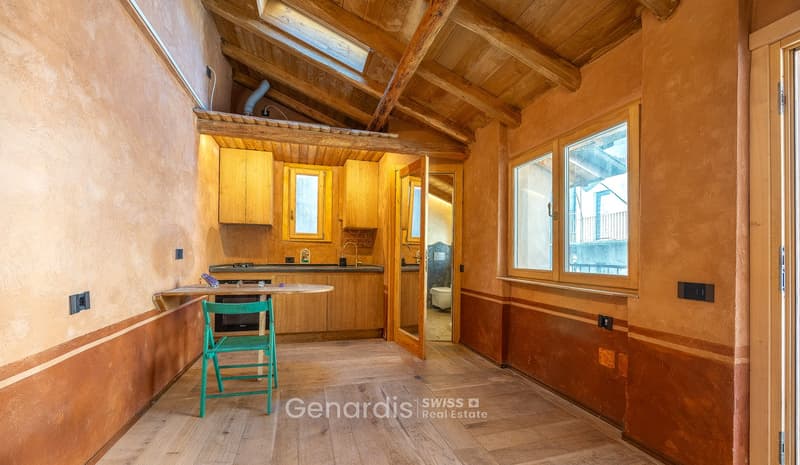 kitchen with wooden cabinets, wooden floor, wooden beams, windows, green chair, table