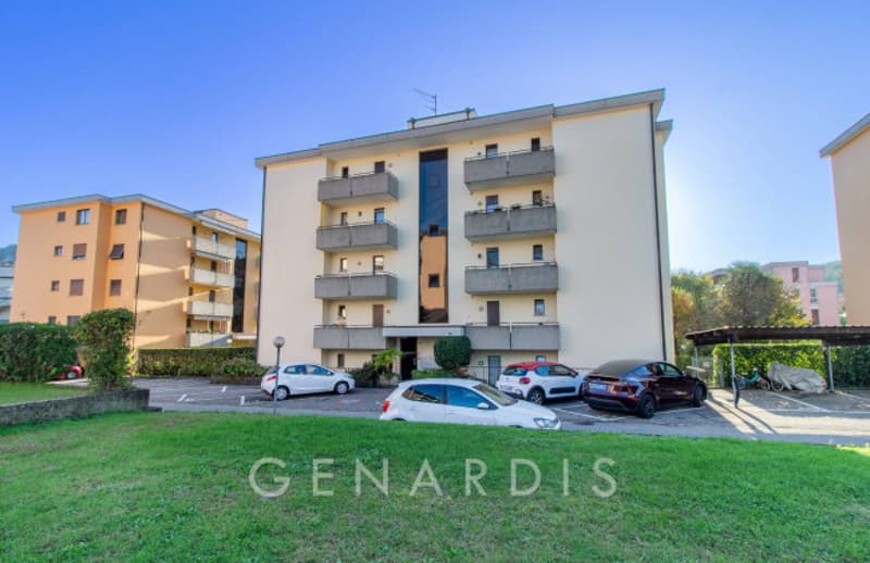 4 story building, beige exterior, multiple balconies, parking lot, multiple cars parked