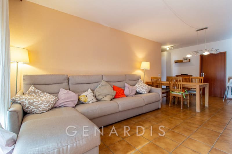 L-shaped sofa, dining table, wooden chairs, lamps, tiled floor, beige walls