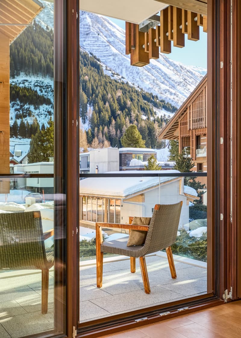 Balcony with wooden chairs, glass door, wooden floor, snowy mountain view