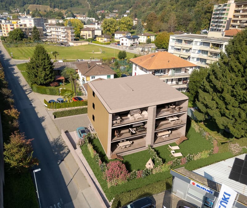 Modern apartment building with multiple floors, balconies, and a parking area.