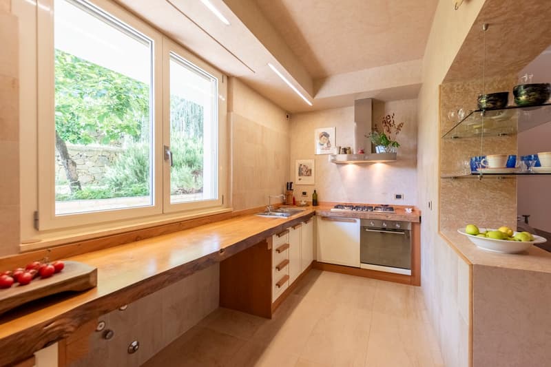 modern kitchen with wooden countertops, white cabinets, gas stove, oven, sink, large window, tiled floor