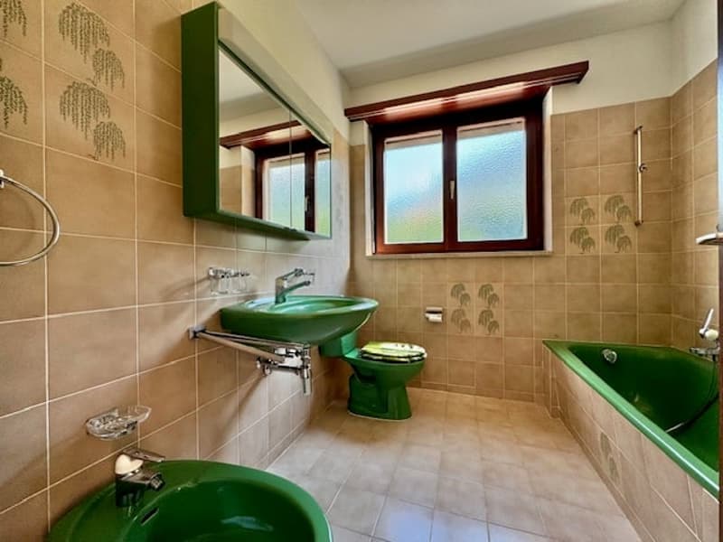 green sink, green toilet, green bathtub, mirror, window, tiled floor, wall-mounted shelves