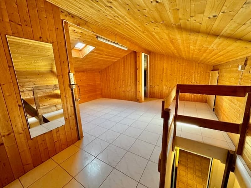 Wooden walls and ceiling, white tiled floor, mirror on the wall, wooden door, wooden staircase