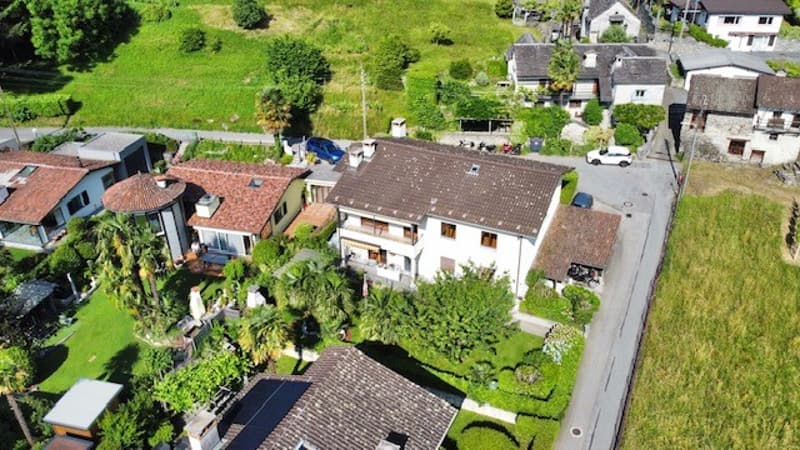 cluster of residential houses, brown roofs, trees, lawn, road