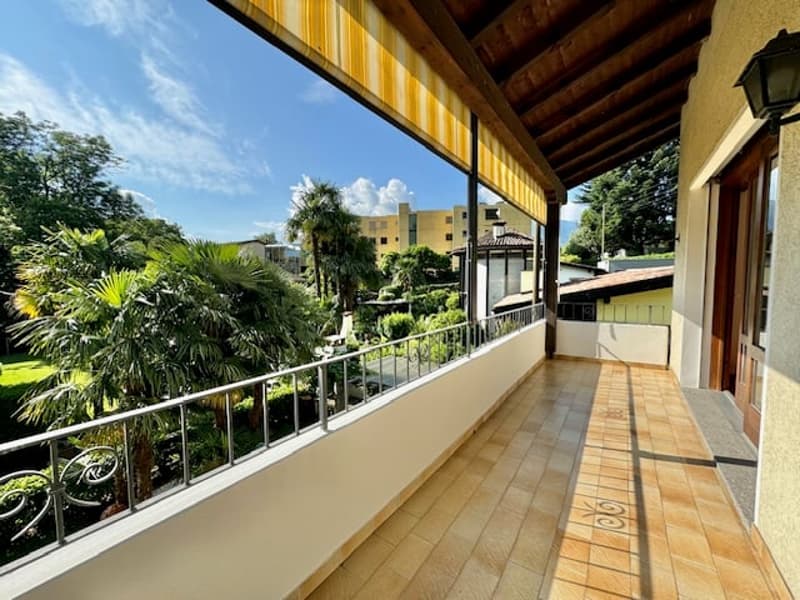 Terraced house with beautiful balcony, covered by a yellow striped awning, view to the garden and city