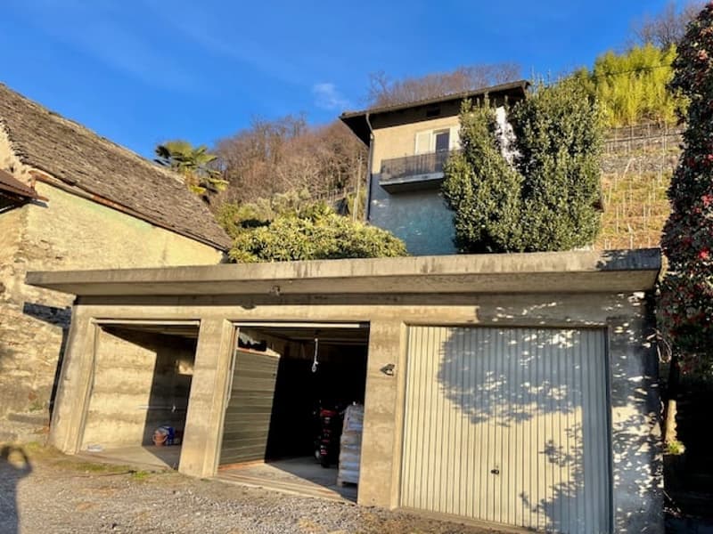 2-story house with a garage and a balcony or terrace, surrounded by vegetation and trees