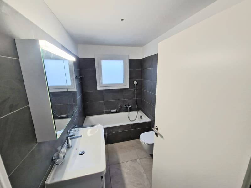 Bathroom with bathtub, toilet, sink, mirror, and windows