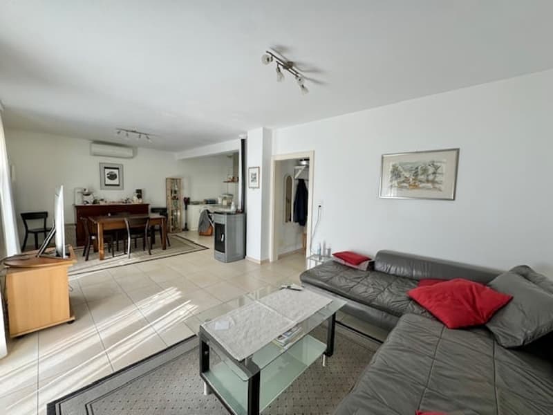 Open-concept living room and dining area, hardwood floors, gray sofa, glass coffee table, kitchen with dishwasher, dining table and chairs