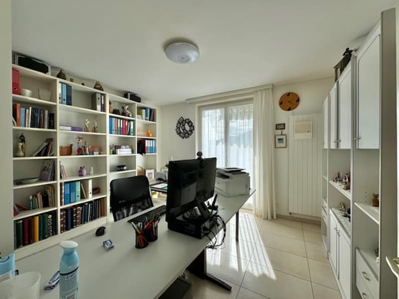 Spacious home office with built-in bookshelves, desk, computer setup, and appliances like a washing machine and dishwasher