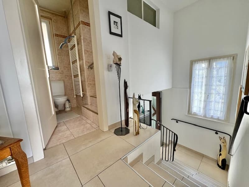 Tiled floor, white walls, bathroom visible, decorative items on the wall