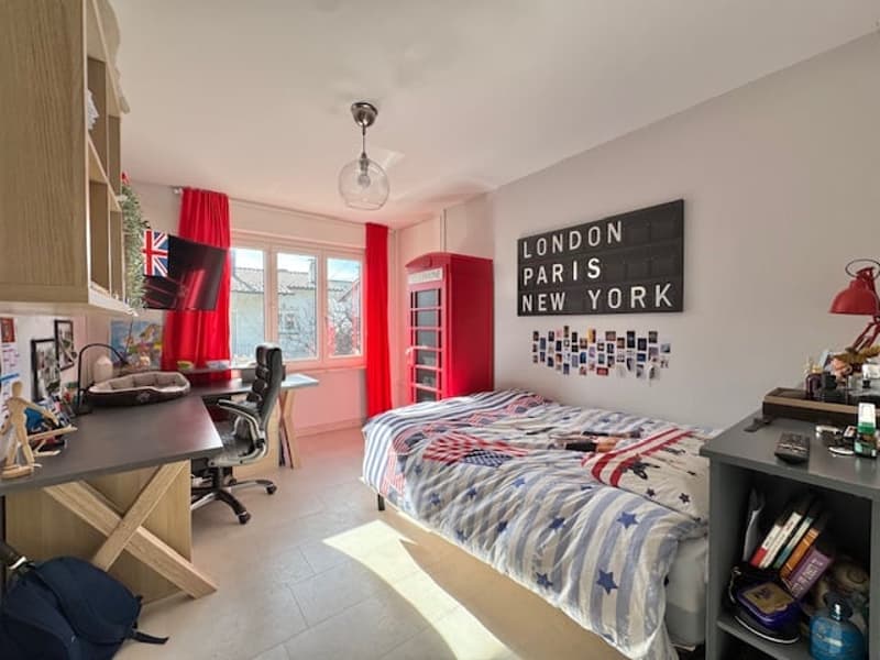 Bedroom with a bed, desk, shelves, and decor featuring London, Paris, and New York themes. The room has a modern and youthful style.