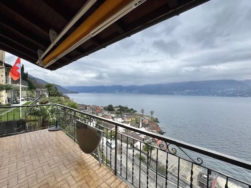 Wooden floor balcony, black iron railings, flag, scenic view of the lake and town