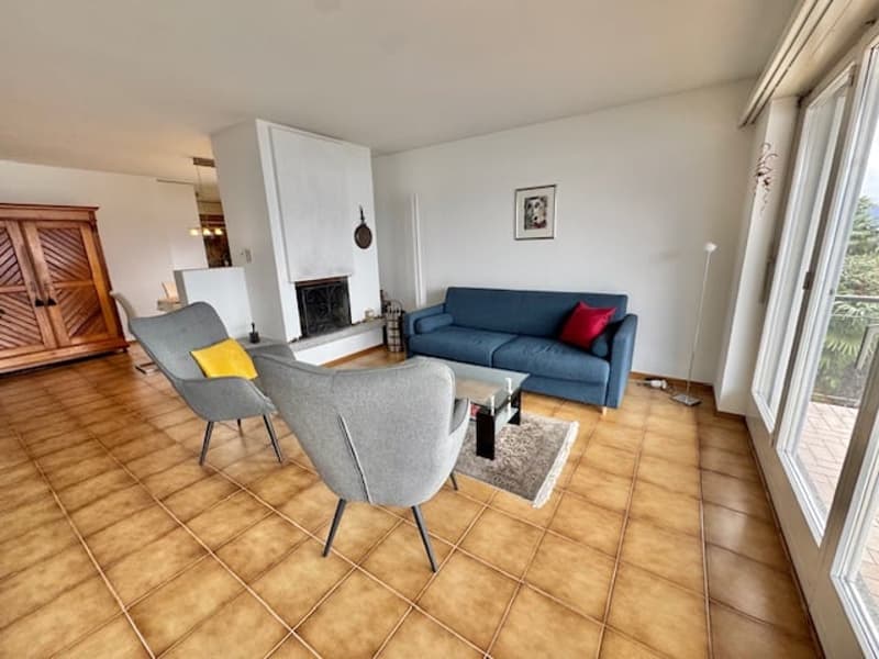 tiled floor, blue couch, red pillow, grey chairs, fireplace, wooden cabinet, glass table, rug, picture frame, lamp