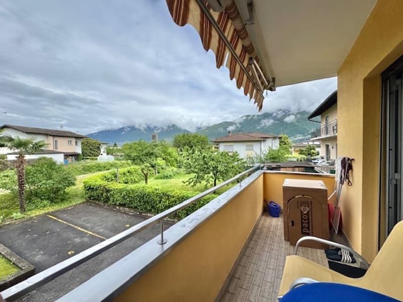 Balcony with a view of the surrounding greenery and mountains, apartment building with yellow exterior walls