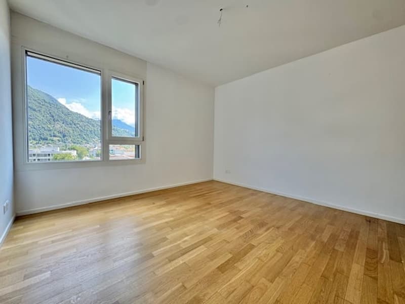 Spacious bedroom with hardwood flooring, large windows providing a scenic view of the surrounding mountains