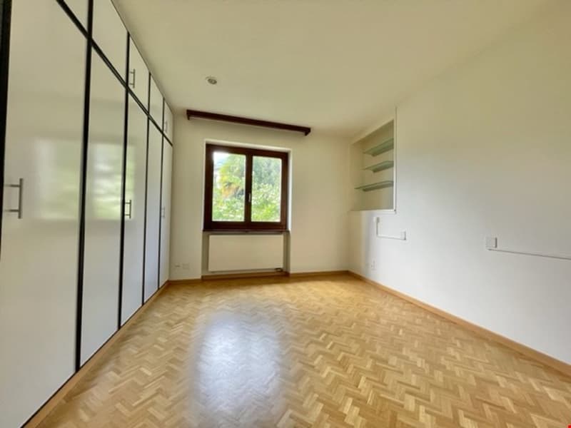 Wooden floor, large window, wardrobe, shelves, white walls, white ceiling
