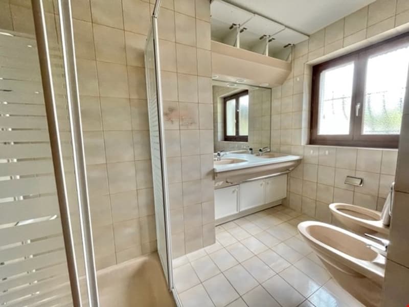 white tiled floor, tiled walls, white sink, double sinks, shower, toilet