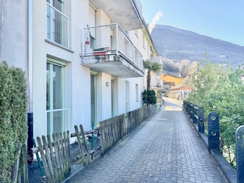 residential building with balcony, white exterior, brick walkway, wooden fence, mountains in the background