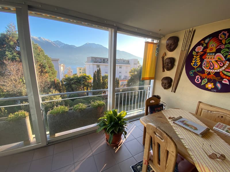 dining room with table and chairs, large windows with view of mountains, decorative masks and objects on wall, potted plants on terrace