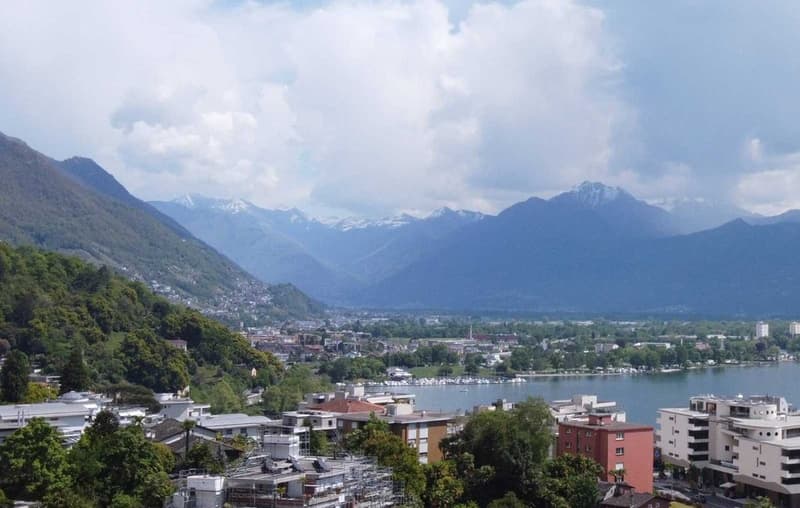 City view with mountains, buildings, and a lake.