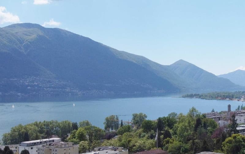 lake, mountain range, sailboats, green trees, distant buildings
