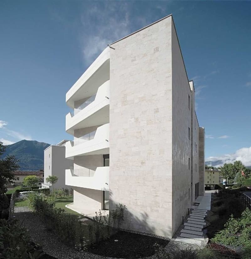 Modern white building with several balconies and staircases leading to the entrance