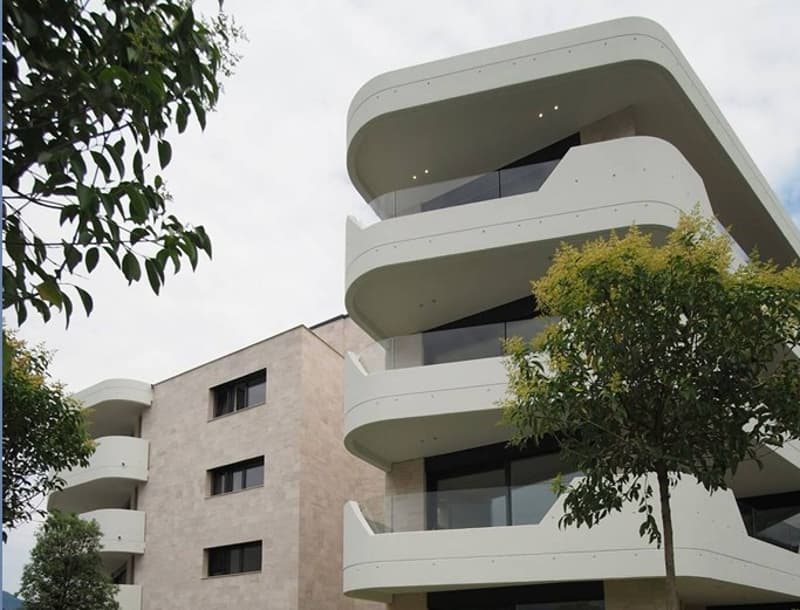 Modern white building, balconies, arched windows, stone and glass exterior