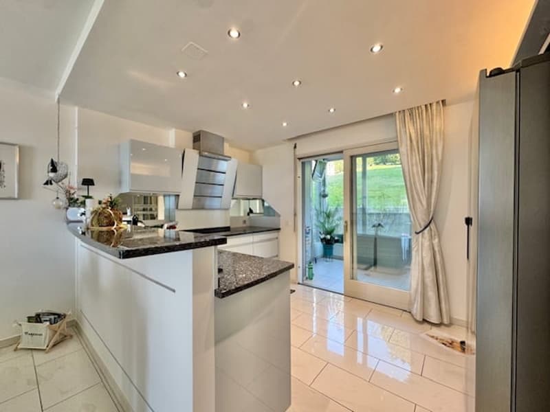modern kitchen with island, granite countertops, white cabinets, stainless steel appliances, sliding glass door to balcony, large windows, tiled floor