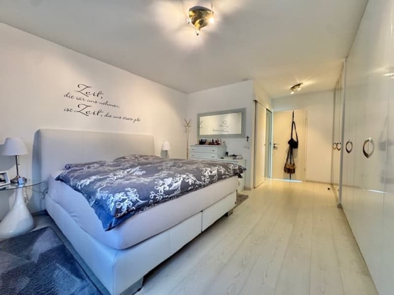 white walls, white bed, white lamp, white table, white floor, white cabinet, mirror, rug