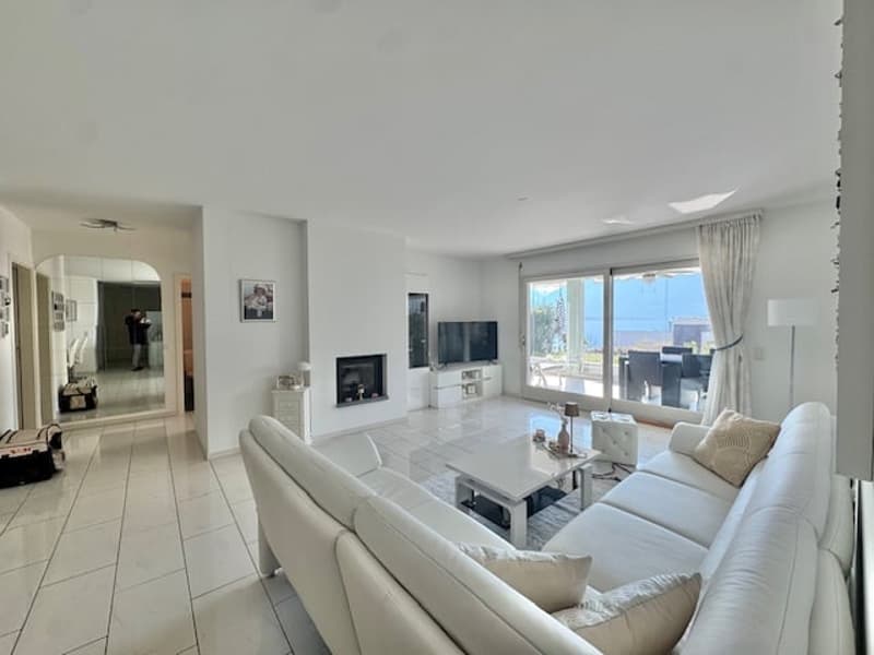 white leather sofa, white coffee table, fireplace, large windows, television, white tile flooring