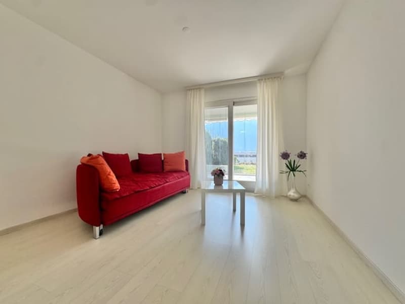 modern living room with red couch, white coffee table, white curtains, white floor, vase with flowers