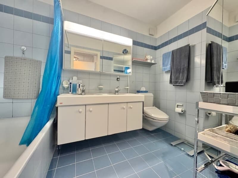 Bathroom with bathtub, sink, toilet, mirror, and blue tiled walls